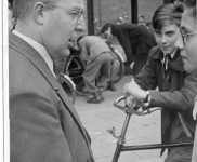 1954 06 vertrek fietsenrally Harry Otten spreekt moed in vreemd afdak op achtergrond nr1947 412x600